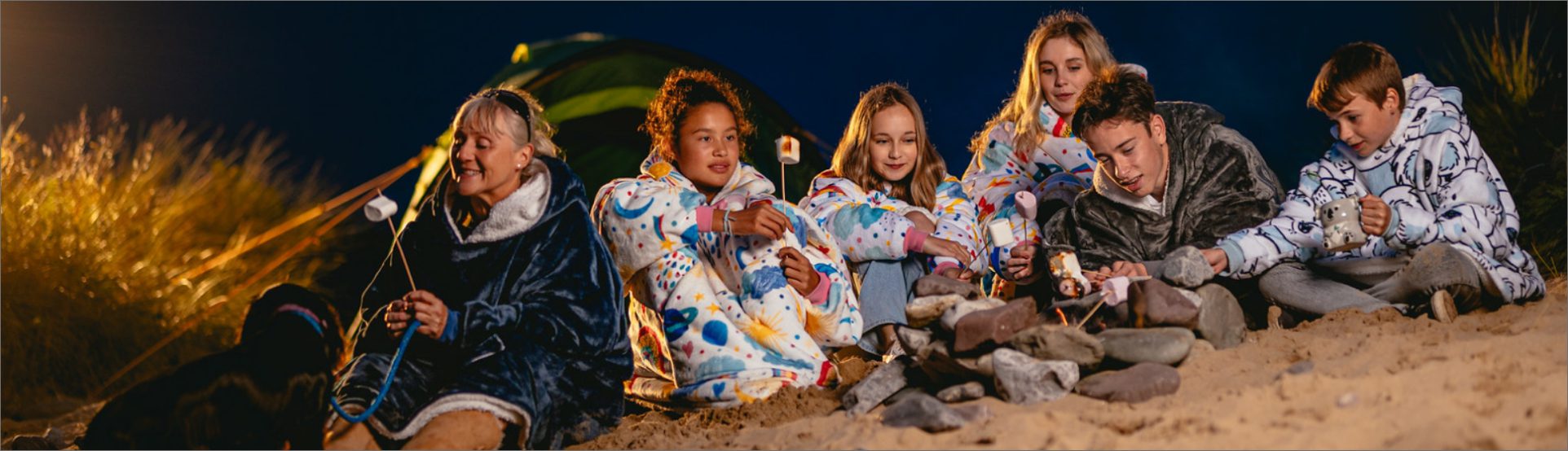 Group shot sitting on beach eating marshmallows